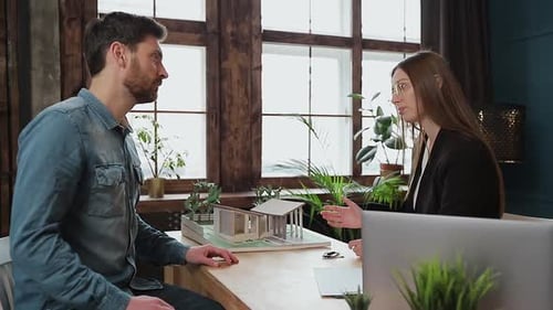 Man Signs Contract at Table with Model House