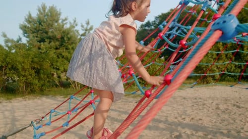 Girl climbing on colorful rope jungle gym