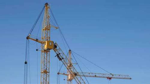 Two Construction Cranes Against the Sky Background.