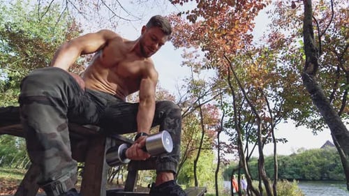 Muscular Man Lifting Weights Outdoors in Park