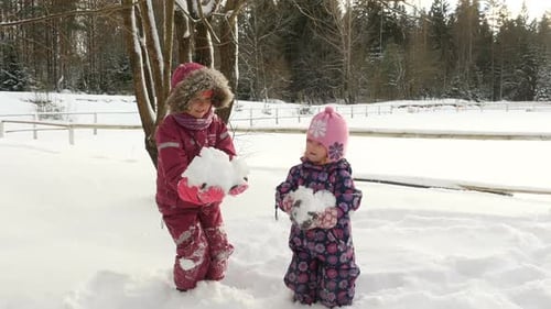 Schöne Kinder werfen eine Handvoll Schnee in die Luft.
