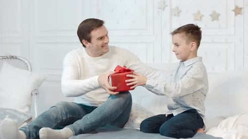 Cheerful Father Presents Gift to Son Indoors