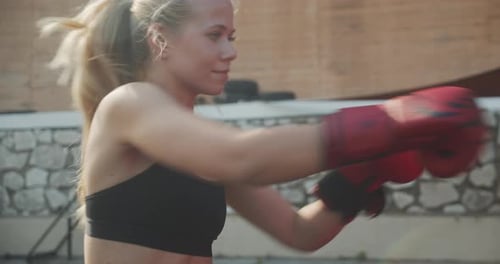 Woman Punching In Boxing Gloves At Outdoor Gym