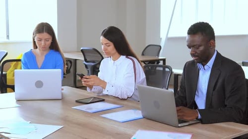 Divers employés assis sur le lieu de travail Personnel utilisant des appareils