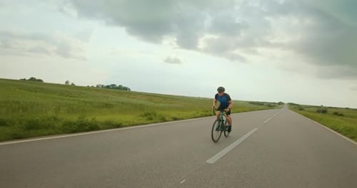 Cyclist Riding Bicycle on Rural Road