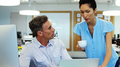 Colleagues Collaborating on Laptop in Modern Office
