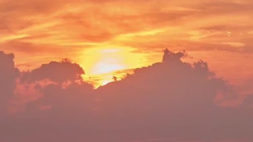 Hot red sun behind silhouettes of evening clouds, time lapse