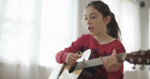 Young Girl Playing Guitar and Singing Indoors