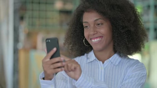 Woman Smiling Using Smartphone Indoors