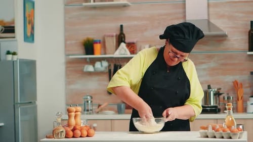 Senior Woman Mixing Dough in Kitchen at Counter