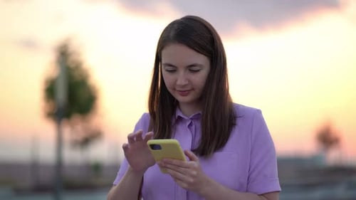 Young Woman Using Phone During Sunset