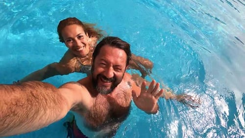 Happy caucasian people couple have fun and enjoy the swimming activity at the pool