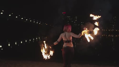 Woman Performs Fire Dance at Night on Shoreline