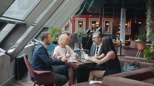 Buiness Partners Men and Women Discussing Deal in Restaurant Talking and Gesturing
