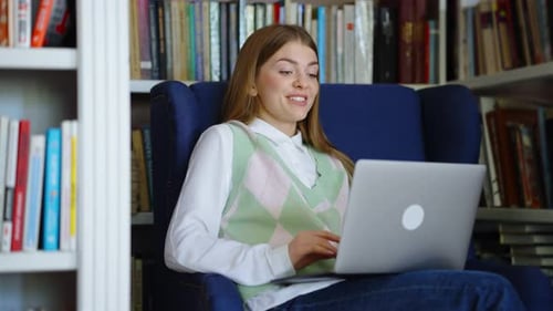 Woman Video Chatting Via Laptop in Library