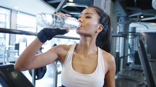 Woman Drinks Water in Modern Gym