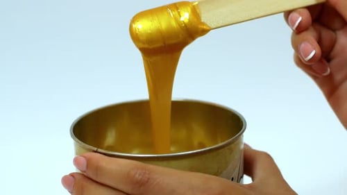 Depilatory wax Master mixes the golden-colored wax. Removing unwanted hair with wax.