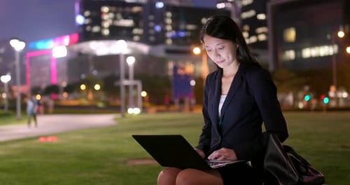 Woman Works On Laptop in City at Night