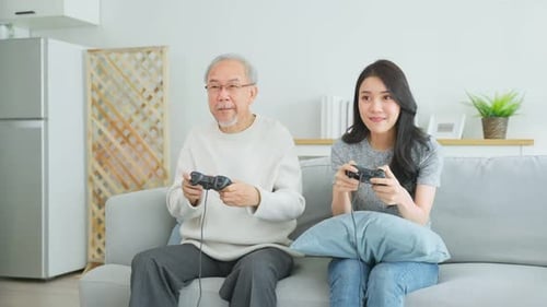 Woman and Senior Man Playing Video Games on Couch