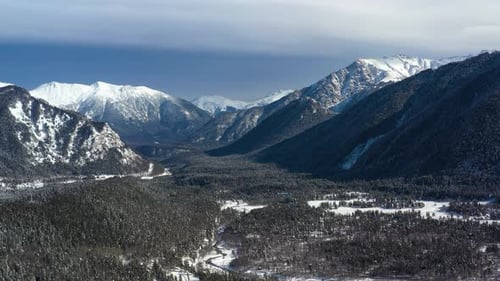 Air Flight Through Mountain Clouds Over Beautiful Snowcapped Peaks of Mountains and Glaciers