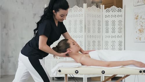Therapeutin macht Behandlung Massage am Hals einer kaukasischen jungen Frau