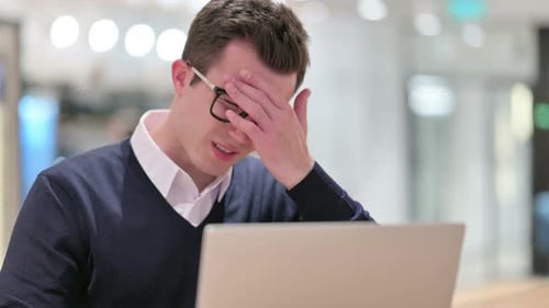 Tired Man Rubbing Eyes While Working at Laptop