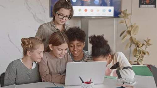 Diverse Children Collaborating on Laptop Project in Classroom