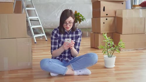 Young Woman Using Phone Amid Moving Boxes
