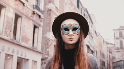 Portrait of Woman with Long Hair and Hat Wearing a Carnival Mask Standing in Venice Street in Italy