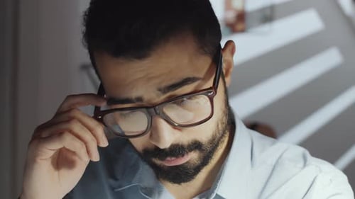 Exhausted Businessman Rubbing Eyes and Working on Laptop Late in Office
