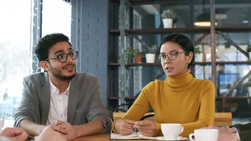 Group of Coworkers Smiling and Discussing Business in Cafe