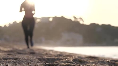 Fit Woman Jogging on Sand of Sea Shore at Sunrise