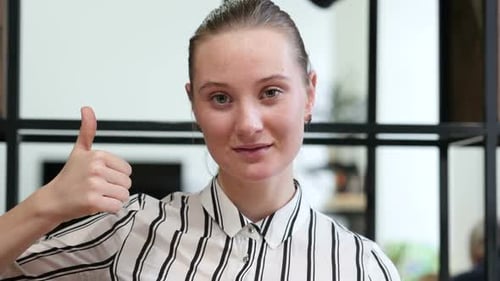 Young Woman Gives Thumbs Up in Office