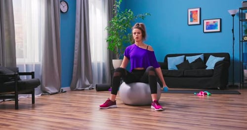 Young Woman Exercising with Dumbbells on Exercise Ball