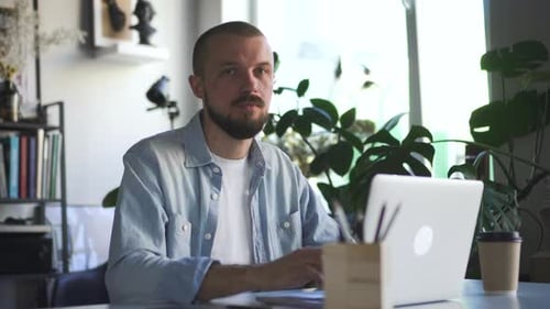 Young Businessman is Working with Laptop and Posing for Camera in White Office