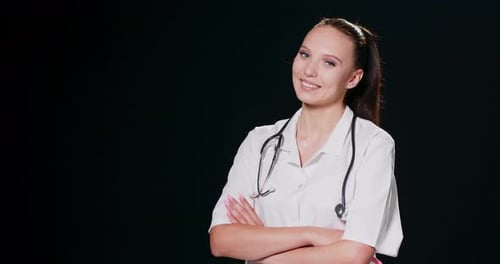 Hermosa mujer caucásica doctora cruzada brazo con sonrisa aislada en fondo negro metáfora