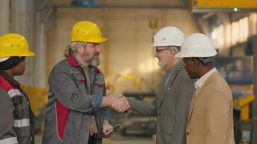 Multiethnic Engineers Shaking Hands and Talking in Factory