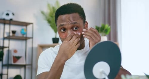 Man Applies Rose Eye Patches at Home