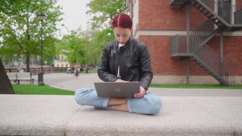 Serious Woman is Working on a Laptop Outdoors in a Beautiful Park