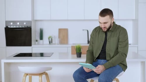 Man Using Tablet Device in Modern White Kitchen