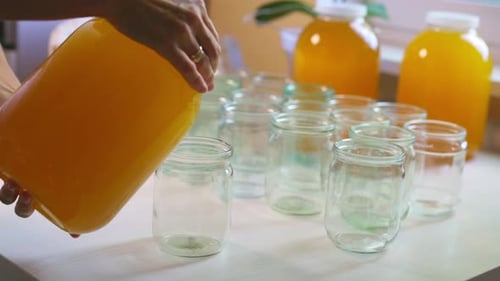 Pouring Yellow Liquid into Glass Jars