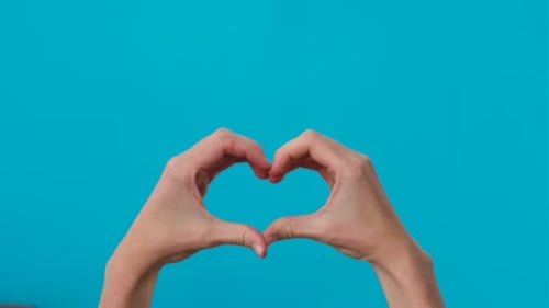Hands Forming Heart on Bright Turquoise Background