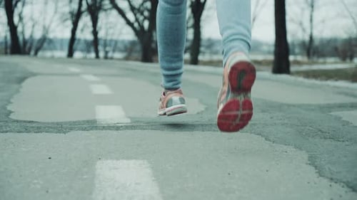Female Feet Jogging on Road in Slow Motion