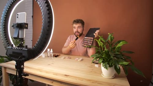 Joven filmando su episodio de videoblog sobre nuevos productos cosméticos mientras
