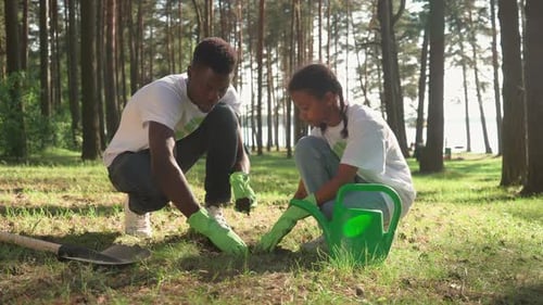 Adult and Child Plant Together in Wooded Area
