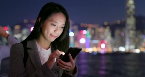 Woman Using Phone in City at Night