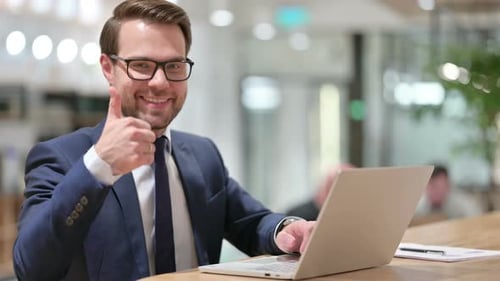 Man Gives Thumbs Up While Working on Laptop
