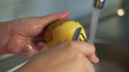 Hands Peeling Potato Under Running Water Close Up