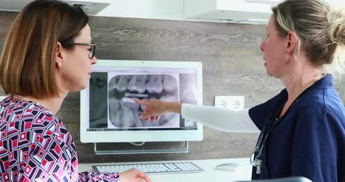 Dentista que explica la imagen de rayos X a una paciente