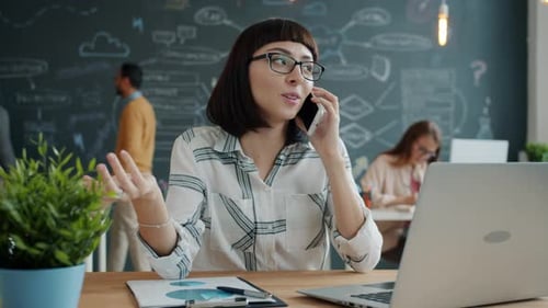 Cheerful Businesswoman Speaking on Mobile Phone Discussing Work in Open Space Office